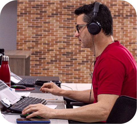 Imagem de um homem com camiseta vermelha olhando para a tela do computador