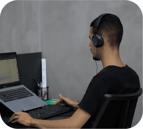 Imagem de um homem sentado de frente para uma mesa olhando para um notebook